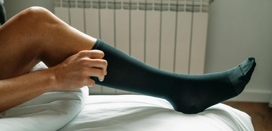 femme qui est entrain d'enfiler une chaussette de compression noire