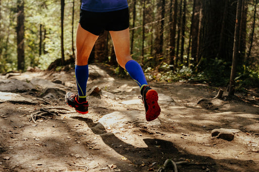 homme qui court dans une foret avec des chaussettes de compression